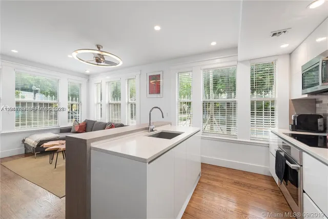 a kitchen that has a sink and a stove with wooden floor