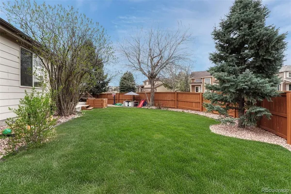a view of a backyard with table and chairs potted plants and large tree