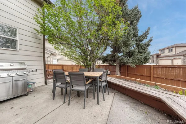 a view of a patio with a dining table and chairs with wooden fence