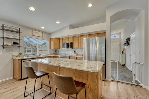 a kitchen with stainless steel appliances granite countertop a table chairs sink refrigerator and cabinets