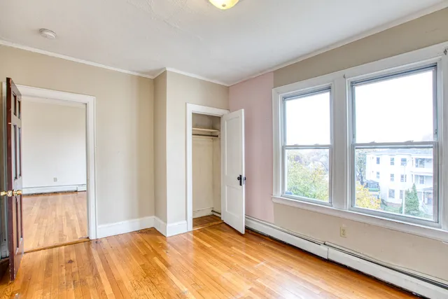 a view of an empty room with wooden floor and a window