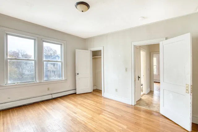 an empty room with wooden floor and windows