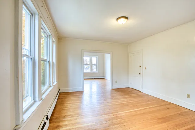 a view of an empty room with wooden floor and a window