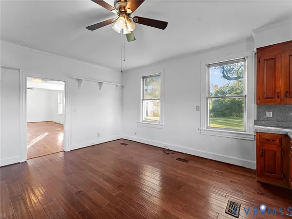 a view of an empty room with wooden floor and a window