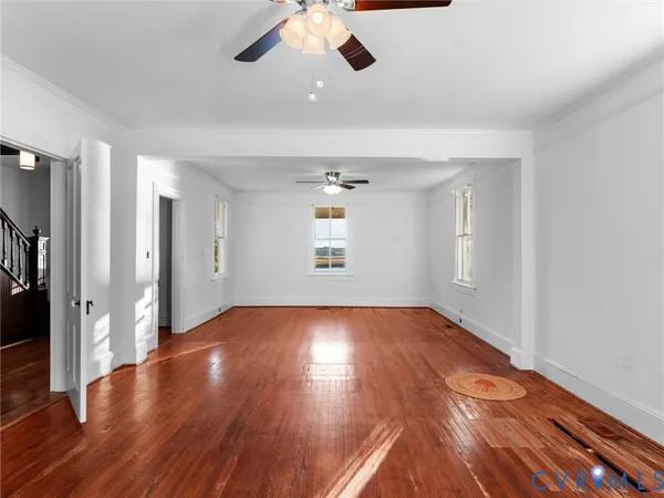 a view of an empty room with wooden floor and a window