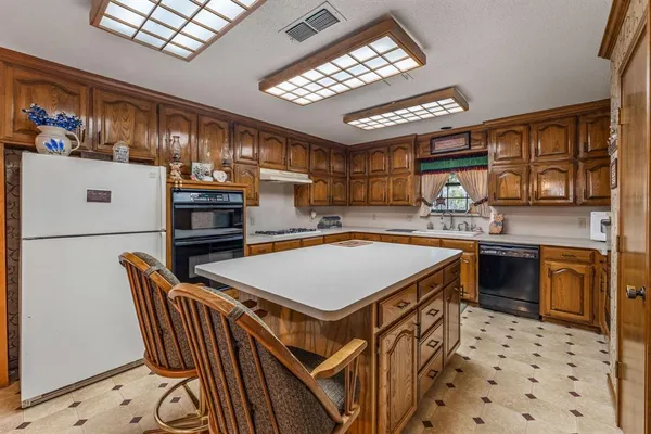 a kitchen with stainless steel appliances kitchen island granite countertop a sink stove and refrigerator