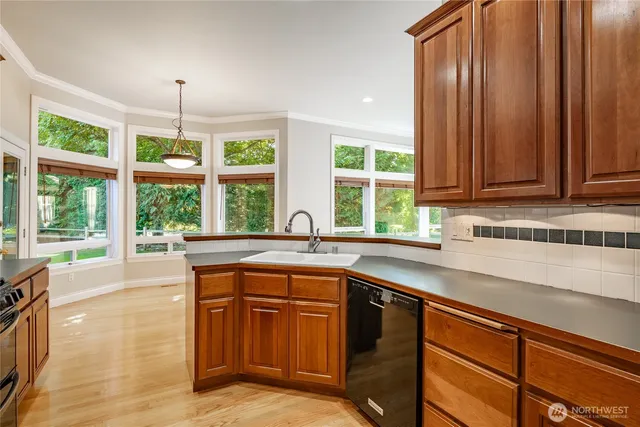 a kitchen with stainless steel appliances granite countertop wooden cabinets a sink and dishwasher with wooden floor