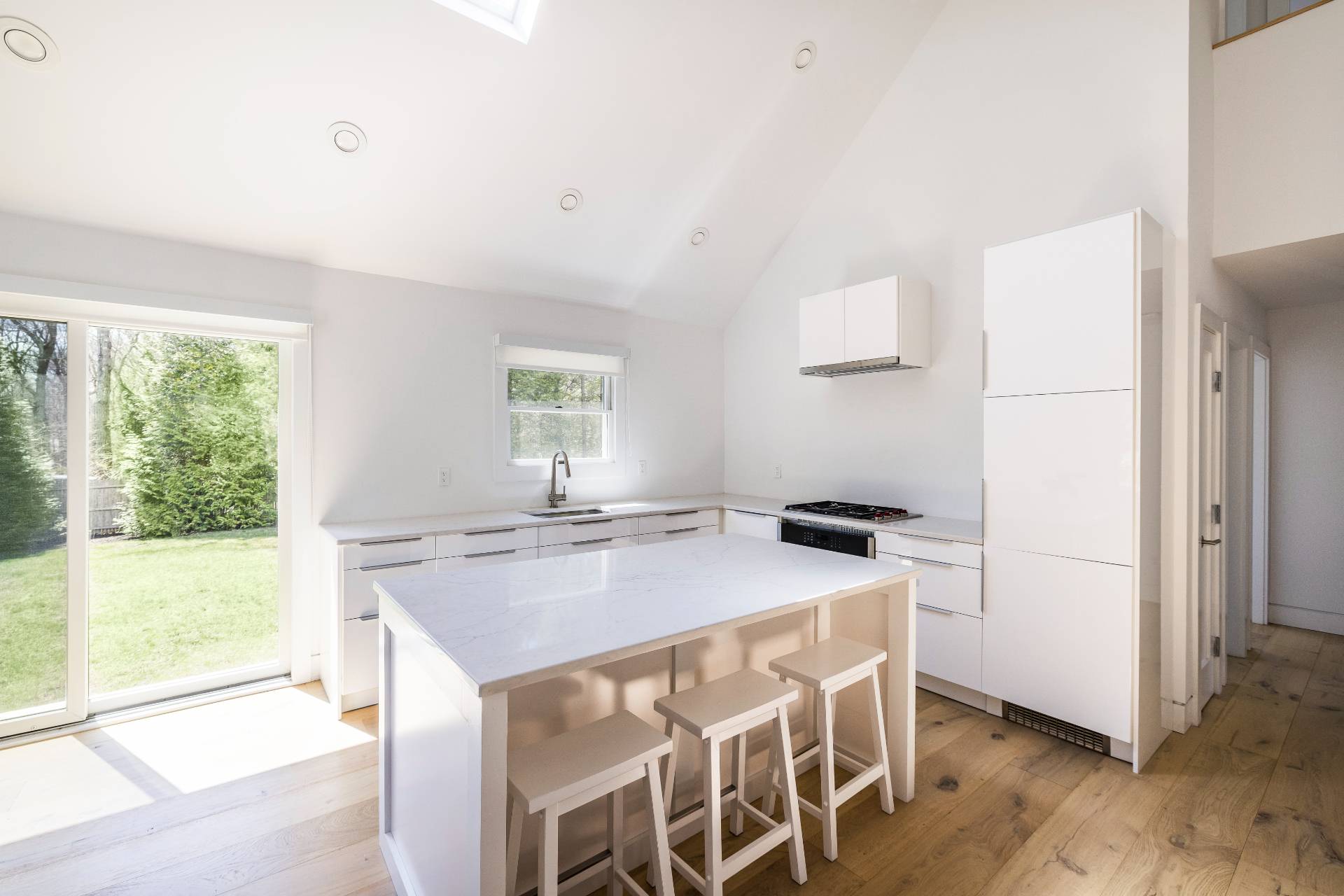 16 Central Avenue East Hampton, NY 11937 - Photo 6 of 16 a kitchen with a stove a refrigerator a sink and a dining table with wooden floor