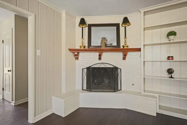 a view of a livingroom with a fireplace a chandelier fan and wooden floor