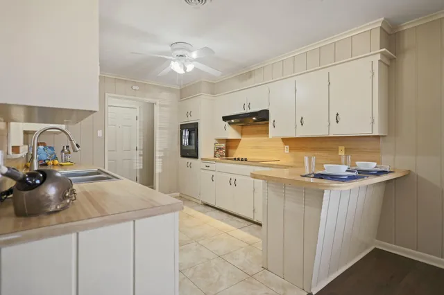 an empty room with wooden floor chandelier fan and windows