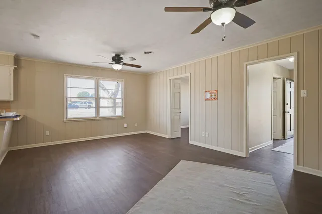 a view of an empty room with window and wooden floor