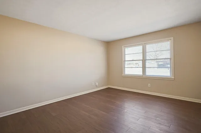 an empty room with wooden floor and ceiling fan