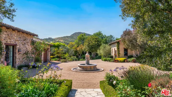 a front view of a house with a yard and fountain