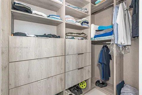 a view of walk in closet with clothes and shoes