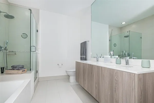 a bathroom with a double vanity sink toilet mirror and shower