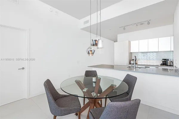 a kitchen with a dining table chairs and white cabinets