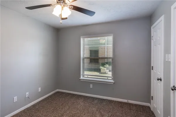 an empty room with a window and a fan