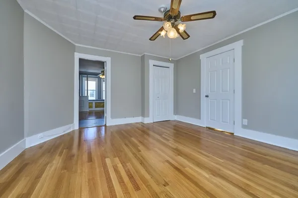 a view of empty room with wooden floor and fan