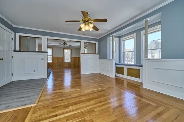 a view of an empty room with wooden floor and a window