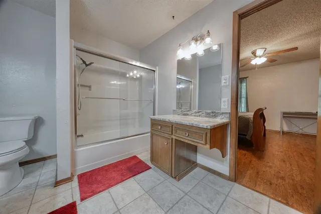 a spacious bathroom with a granite countertop sink a toilet a mirror and shower