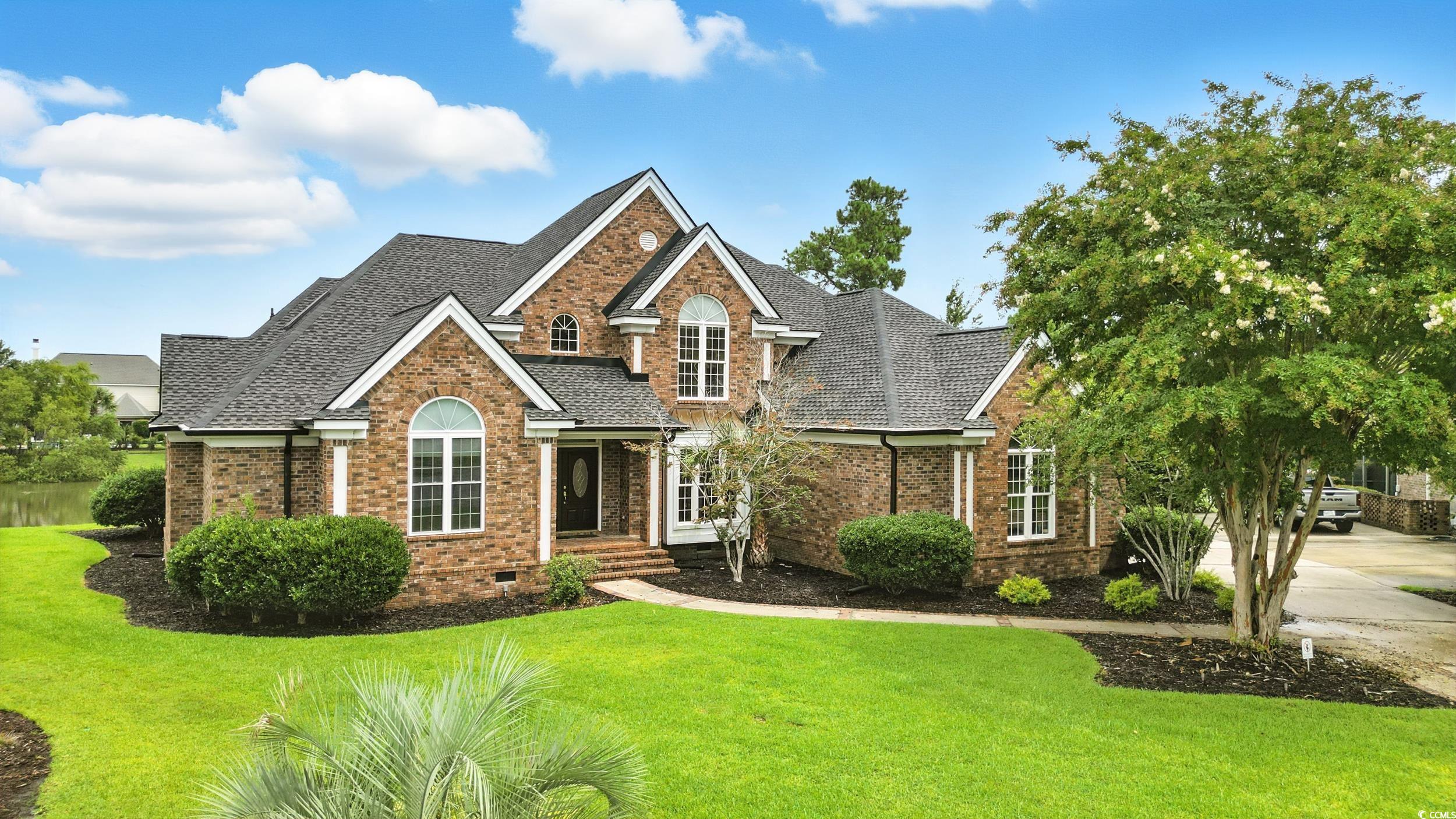 View of front of home with brick siding, crawl space, a front lawn, and roof with shingles