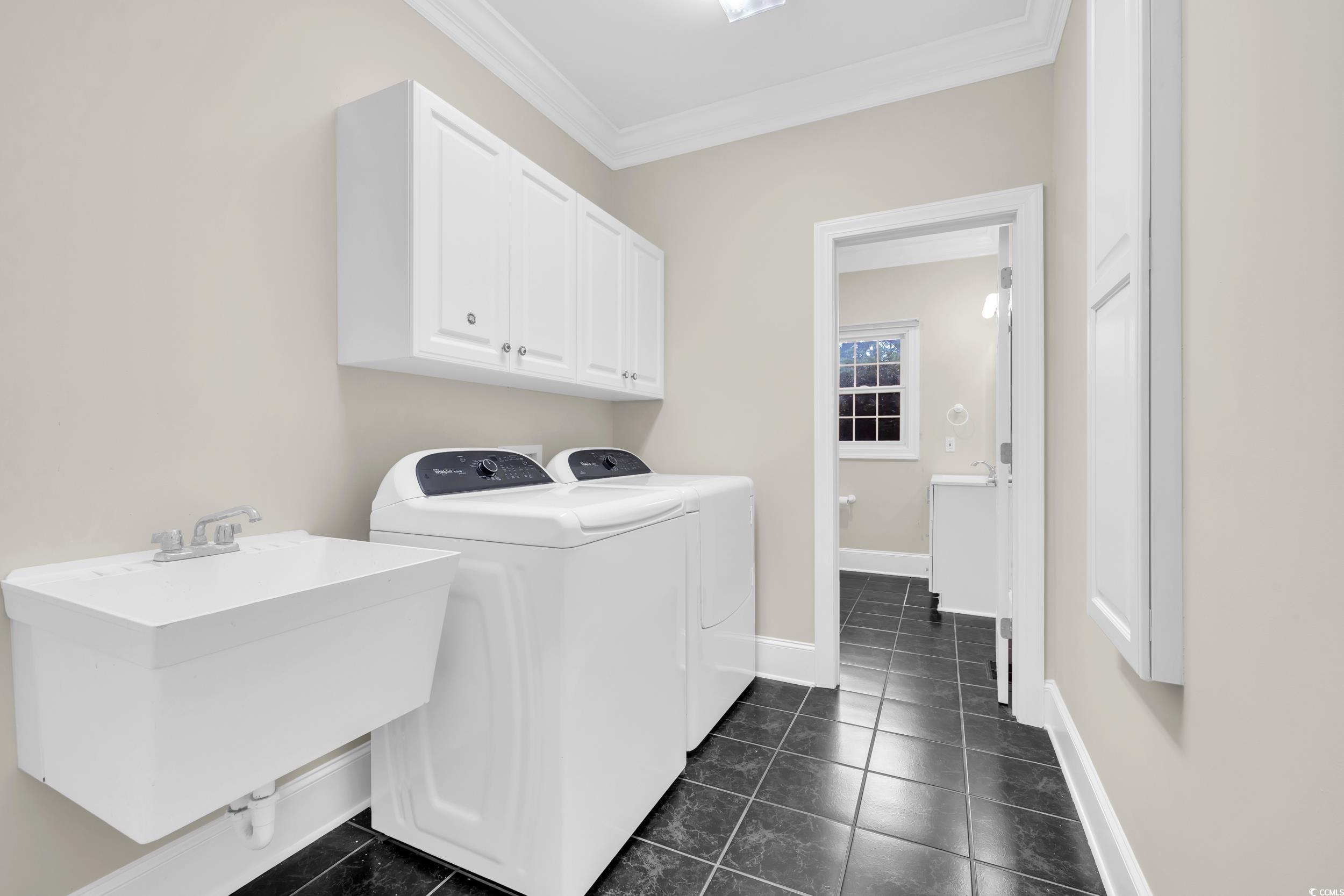 1473 Doar Point Myrtle Beach, SC 29577 - Photo 18 of 40 Washroom featuring washer and clothes dryer, ornamental molding, dark tile patterned floors, and cabinet space
