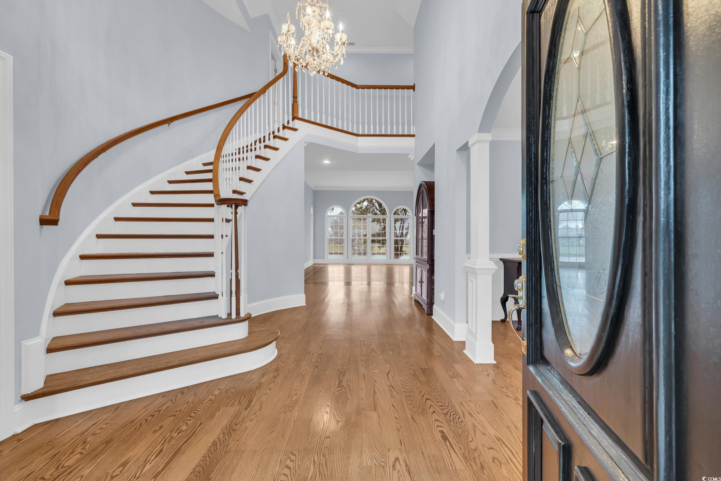 1473 Doar Point Myrtle Beach, SC 29577 - Photo 4 of 40 Entryway with a towering ceiling, a chandelier, wood finished floors, crown molding, and arched walkways