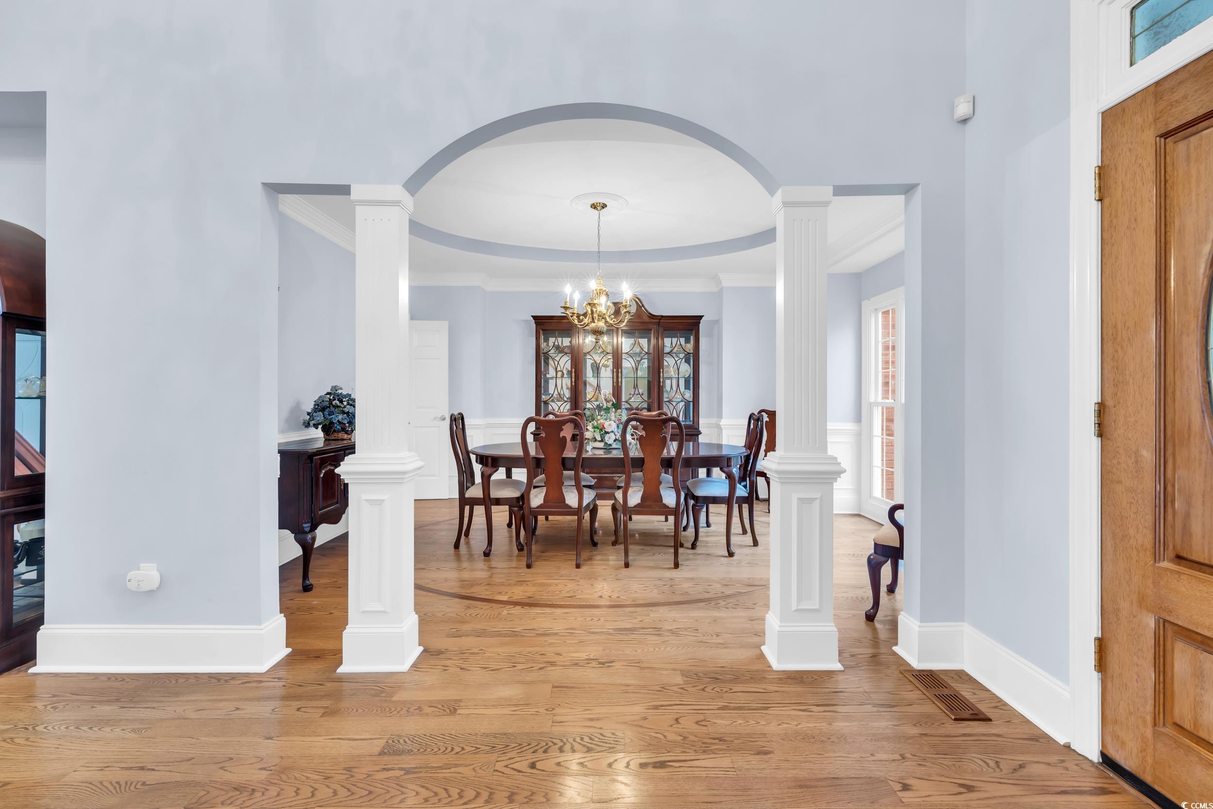 1473 Doar Point Myrtle Beach, SC 29577 - Photo 6 of 40 Dining area featuring light wood finished floors, a chandelier, arched walkways, a tray ceiling, and ornamental molding