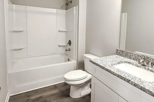 a bathroom with a granite countertop toilet a sink and a bathtub