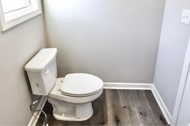 a white toilet sitting next to a wooden floor