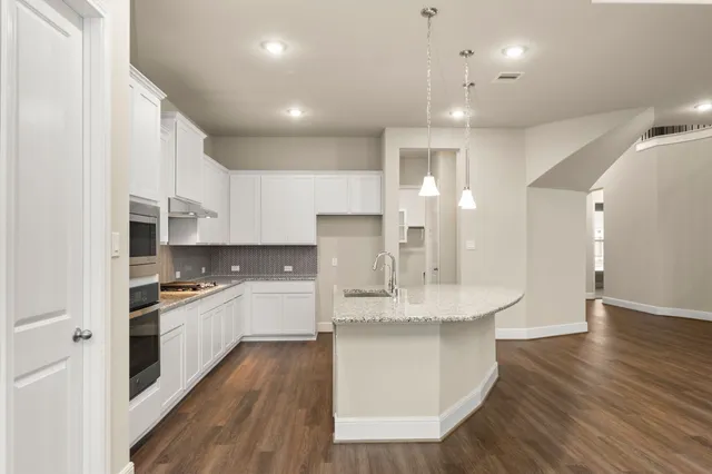 a large kitchen with stainless steel appliances kitchen island granite countertop a lot of counter space and wooden floors