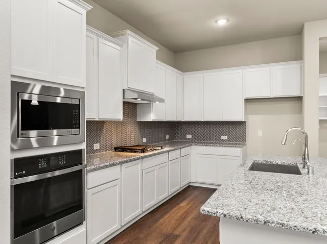a kitchen with stainless steel appliances granite countertop a sink stove and microwave