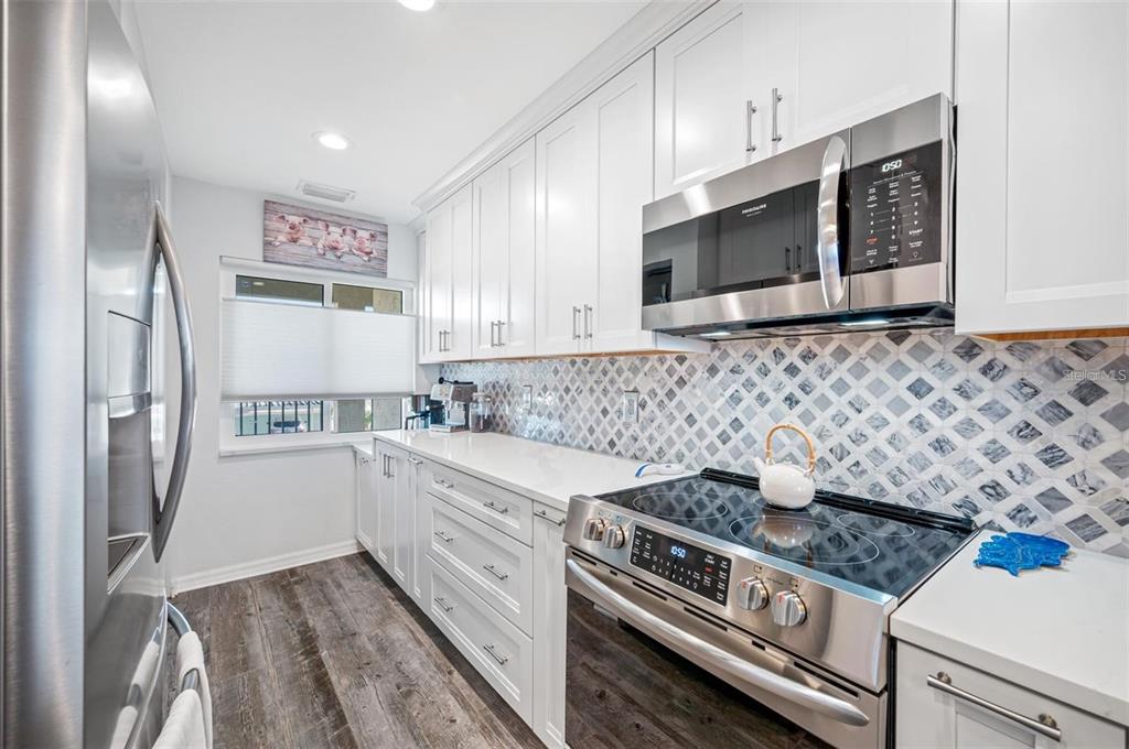 8251 Brent Street, Unit 912 Port Richey, FL 34668 - Photo 11 of 84 a kitchen with stainless steel appliances granite countertop a stove a microwave and a refrigerator