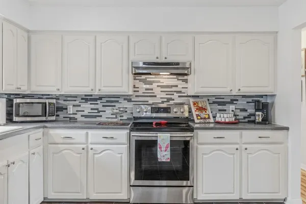 a kitchen with granite countertop white cabinets and stainless steel appliances