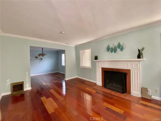 a view of an empty room with wooden floor and a fireplace