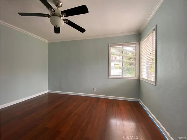 an empty room with wooden floor fan and windows