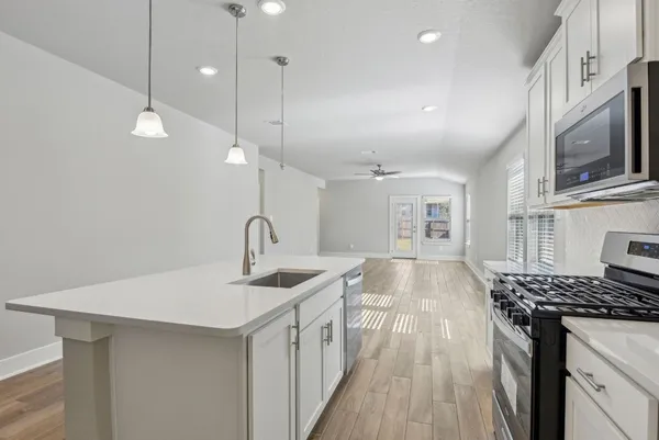 a kitchen with stainless steel appliances granite countertop a sink a stove and a wooden floors