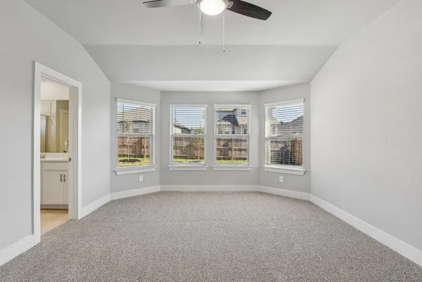 an empty room with chandelier fan and windows