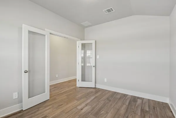 a view of an empty room with wooden floor and closet