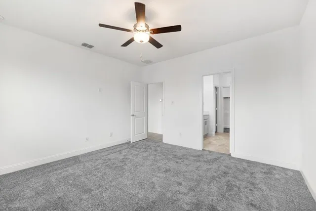 an empty room with windows and ceiling fan