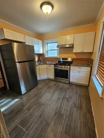a kitchen with granite countertop a refrigerator stove and wooden floor