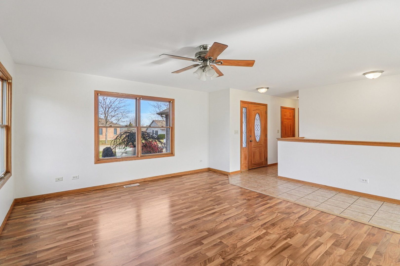 905 Randall Court Marengo, IL 60152 - Photo 11 of 28 an empty room with wooden floor ceiling fan and windows