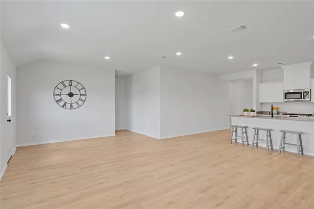 a view of kitchen with kitchen island stainless steel appliances refrigerator stove and white cabinets