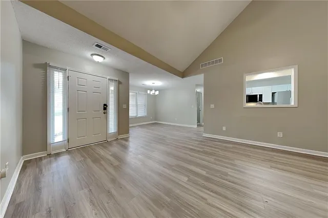a view of an empty room with wooden floor and a window