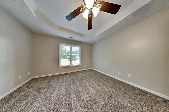 an empty room with a chandelier fan and windows