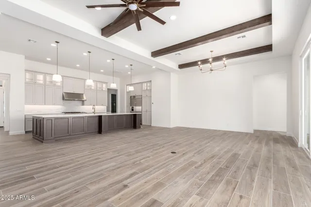 a view of an empty room with kitchen and a window