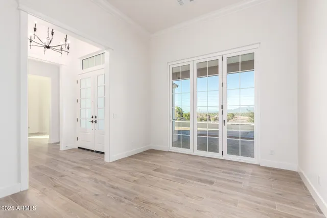 an empty room with wooden floor chandelier fan and windows