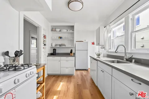 a kitchen with white cabinets a sink dishwasher and a stove with wooden floor
