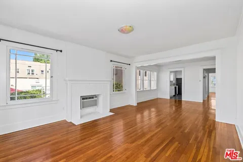 a view of an empty room with window and wooden floor