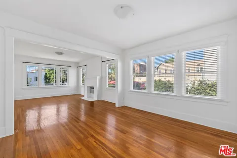 a view of empty room with wooden floor and fan